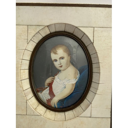 15 - A 19TH CENTURY BONE FRAMED OVAL MINIATURE PORTRAIT, depicting and infant, semi-reclined on blue cush... 