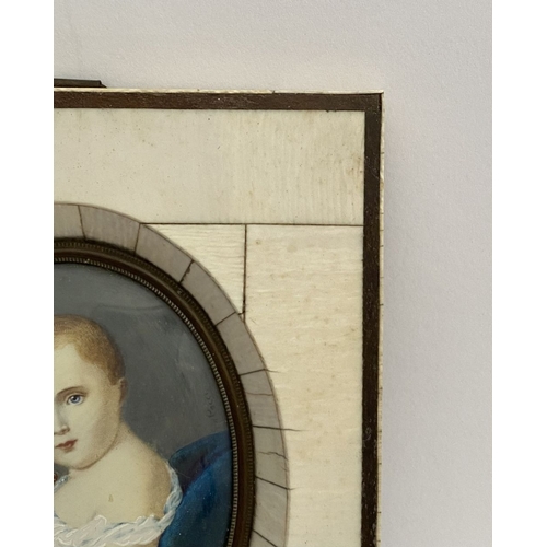 15 - A 19TH CENTURY BONE FRAMED OVAL MINIATURE PORTRAIT, depicting and infant, semi-reclined on blue cush... 