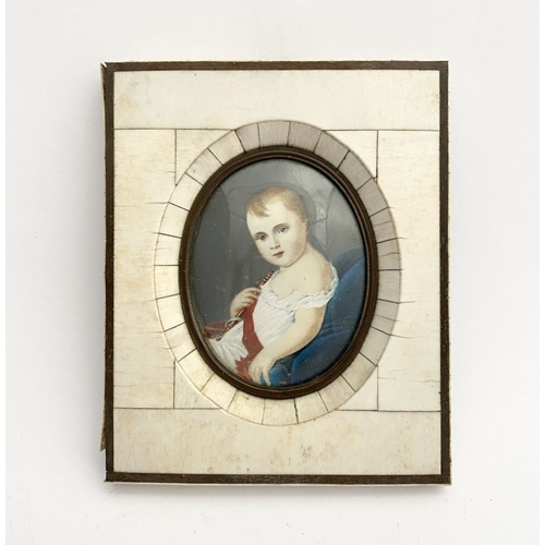 15 - A 19TH CENTURY BONE FRAMED OVAL MINIATURE PORTRAIT, depicting and infant, semi-reclined on blue cush... 