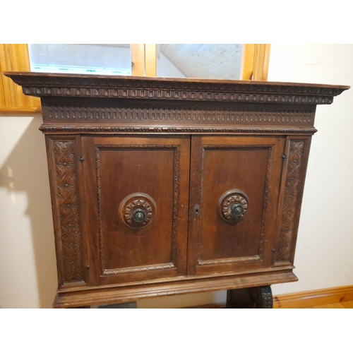 155 - A MAHOGANY TWO DOOR CABINET, with carved cornice above two panelled doors, opening to shelving, rais... 