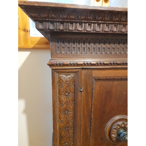 155 - A MAHOGANY TWO DOOR CABINET, with carved cornice above two panelled doors, opening to shelving, rais... 