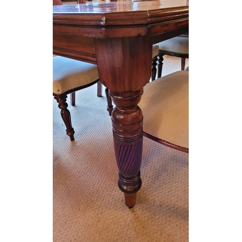 215 - A GOOD QUALITY 20TH CENTURY MAHOGANY DINING TABLE, with canted corners and raised on beautiful turne... 