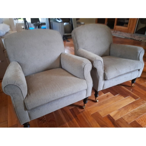 286 - A PAIR OF GREY UPHOLSTERED ARMCHAIRS, on turned leg with castors. Dimensions: 84cm wide x 82cm high ... 