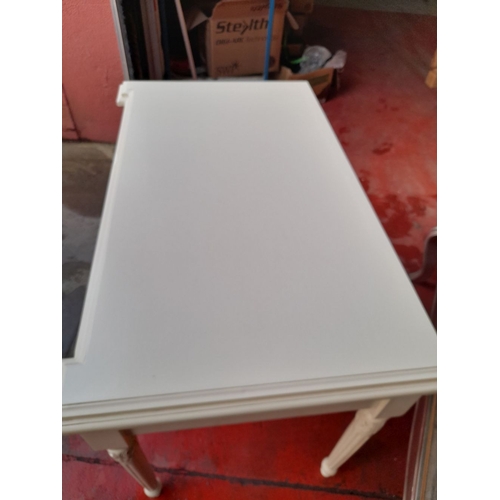 290 - A WHITE PAINTED ONE DRAWER DESK, with shaped top, one long drawer with drop handles, raised on flute... 