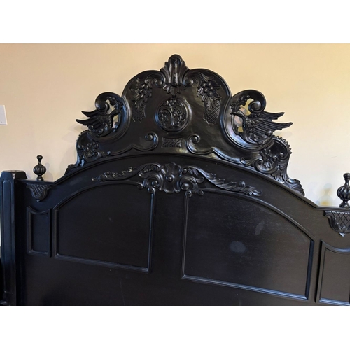 298 - A BLACK PAINTED CARVED HEADBOARD & FRAME, the headboard with carved mount to centre, between two fin... 