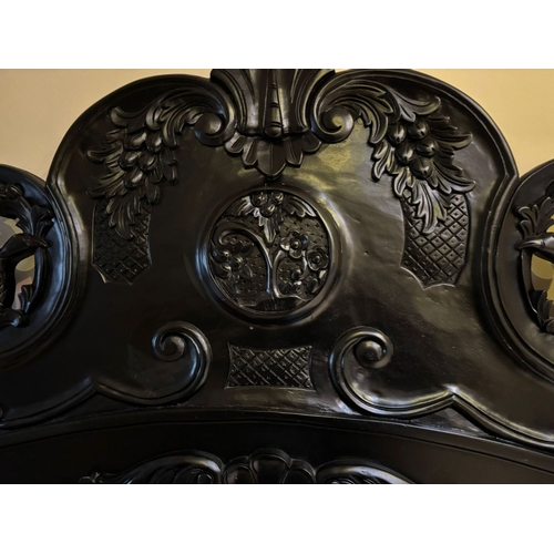 298 - A BLACK PAINTED CARVED HEADBOARD & FRAME, the headboard with carved mount to centre, between two fin... 