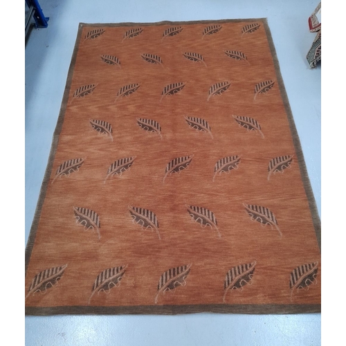 326 - A VINTAGE LEAF PATTERN RUG, multiple leaf motifs on orange ground. In good condition. Dimensions: 24... 