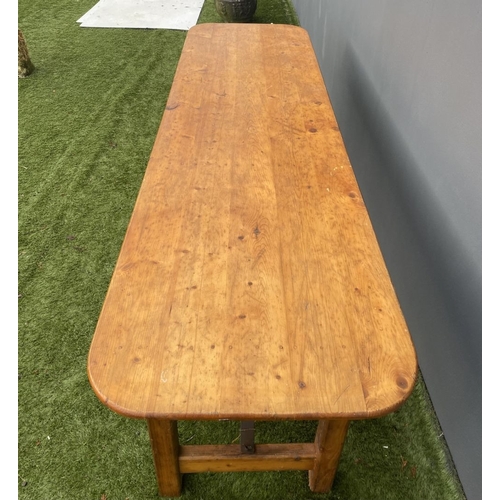 329 - A LARGE PINE TRESTLE TABLE, long rectangular top with canted corners, raised on four straight legs j... 