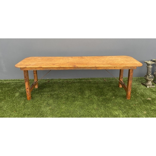 329 - A LARGE PINE TRESTLE TABLE, long rectangular top with canted corners, raised on four straight legs j... 