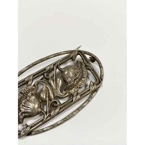 62 - A BEAUTIFUL ART NOUVEAU STERLING SILVER FLOWER BROOCH, featuring two flowers within openwork rectang... 