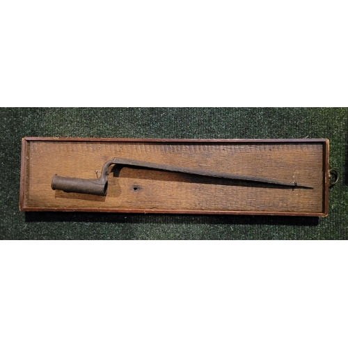 69 - AN ANTIQUE TRIANGULAR SOCKET BAYONET, mounted on an oak panel. Indistinct possible maker’s name to t... 