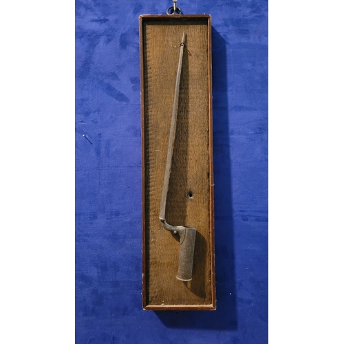 69 - AN ANTIQUE TRIANGULAR SOCKET BAYONET, mounted on an oak panel. Indistinct possible maker’s name to t... 