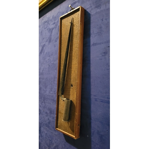 69 - AN ANTIQUE TRIANGULAR SOCKET BAYONET, mounted on an oak panel. Indistinct possible maker’s name to t... 