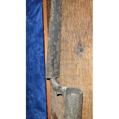 69 - AN ANTIQUE TRIANGULAR SOCKET BAYONET, mounted on an oak panel. Indistinct possible maker’s name to t... 