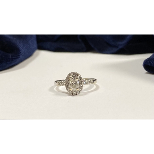 71 - A STUNNING 14CT WHITE GOLD DIAMOND CLUSTER RING, with central oval brilliant cut diamond, weight: .5... 