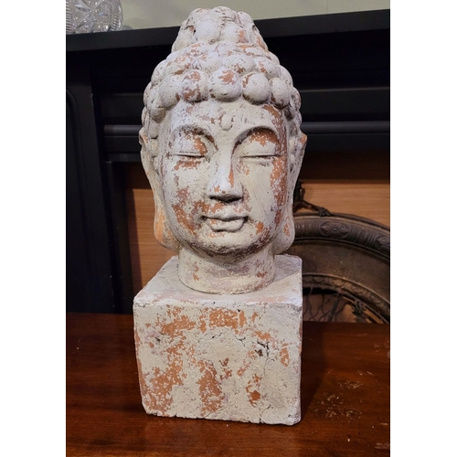 73 - A DECORATIVE ORNAMENT CLAY BUDDHA HEAD, the detailed face resting upon a square plinth hollow base. ... 