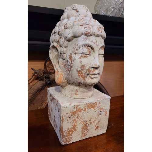 73 - A DECORATIVE ORNAMENT CLAY BUDDHA HEAD, the detailed face resting upon a square plinth hollow base. ... 