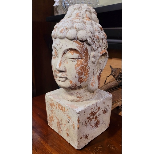 73 - A DECORATIVE ORNAMENT CLAY BUDDHA HEAD, the detailed face resting upon a square plinth hollow base. ... 