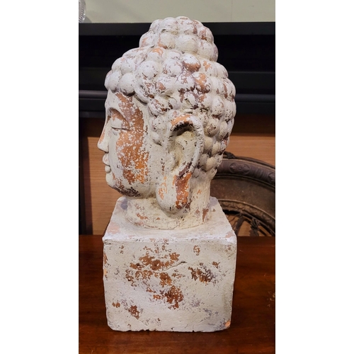 73 - A DECORATIVE ORNAMENT CLAY BUDDHA HEAD, the detailed face resting upon a square plinth hollow base. ... 