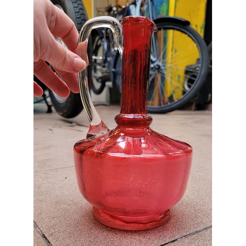 192 - A VERY GOOD ANTIQUE CRANBERRY GLASS DECANTER JUG, with clear glass curved handle, in very good/excel... 