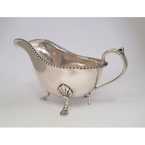 9 - AN IRISH CORK SILVER SAUCE BOAT, with gadrooned edge, a scroll shaped handle resting on a tripod leg... 