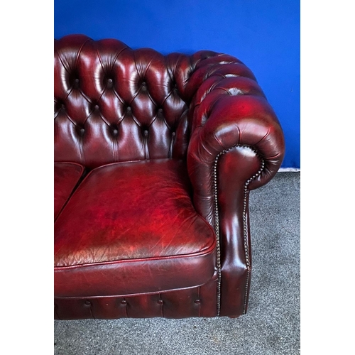 117 - AN EXCELLENT OXBLOOD LEATHER THREE-SEATER CHESTERFIELD COUCH, with arched back and scroll armrests, ... 