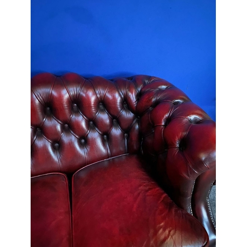 117 - AN EXCELLENT OXBLOOD LEATHER THREE-SEATER CHESTERFIELD COUCH, with arched back and scroll armrests, ... 