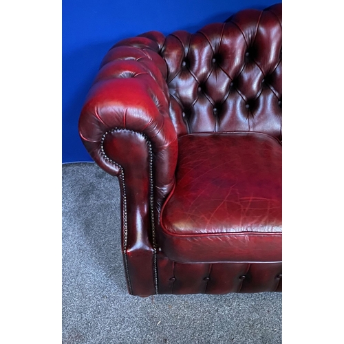 117 - AN EXCELLENT OXBLOOD LEATHER THREE-SEATER CHESTERFIELD COUCH, with arched back and scroll armrests, ... 