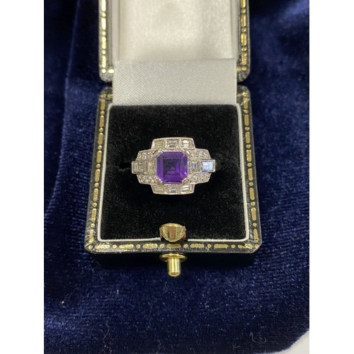 132 - AN 18CT WHITE GOLD AMETHYST & DIAMOND RING, the central amethyst is set in a four prong claw setting... 