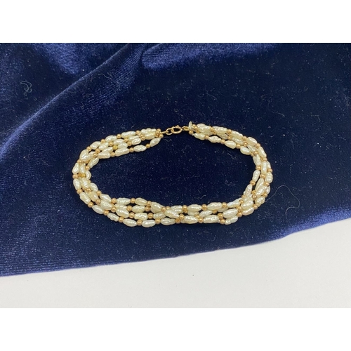 147 - A PRETTY 9CT GOLD FOUR STRAND PEARL BRACELET, each strand featuring freshwater baroque shaped pearls... 