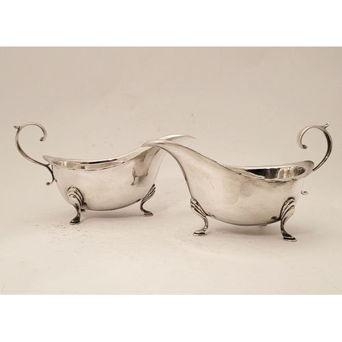 154 - A FINE PAIR OF SILVER SAUCE BOATS, with scalloped rim and open scroll handles, each sitting proudly ... 