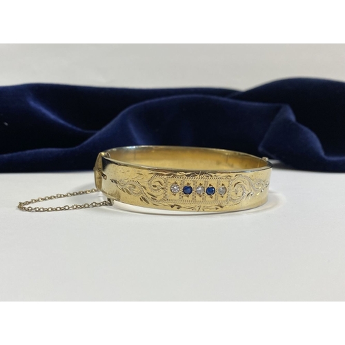 164 - A BEAUTIFUL 9CT GOLD PLATED GEMSET BANGLE BRACELET, with two round cut blue gemstones and three roun... 