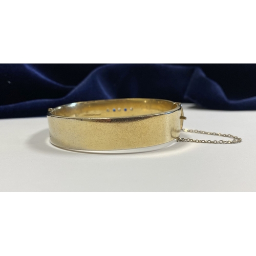 164 - A BEAUTIFUL 9CT GOLD PLATED GEMSET BANGLE BRACELET, with two round cut blue gemstones and three roun... 