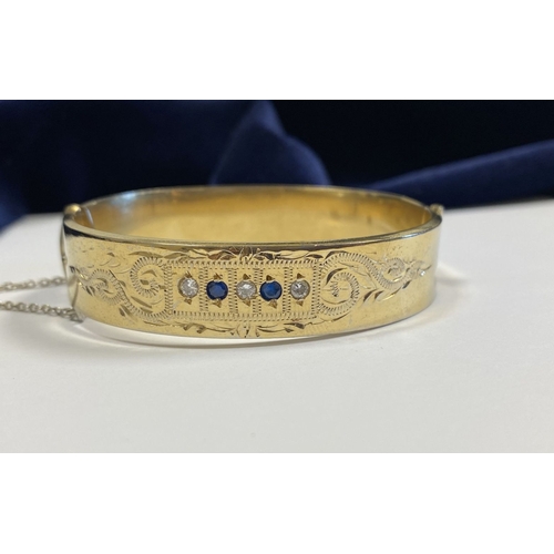 164 - A BEAUTIFUL 9CT GOLD PLATED GEMSET BANGLE BRACELET, with two round cut blue gemstones and three roun... 