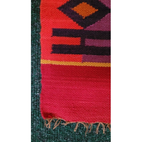 185 - A TRADITIONAL COLOMBIAN BRIGHTLY COLOURED WOVEN WALL HANGING, to the centre are three figures in tra... 