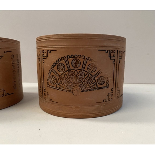 199 - A PAIR OF CHINESE RED CLAY CANNISTERS, cylindrical form, the sides decorated with panels depicting f... 