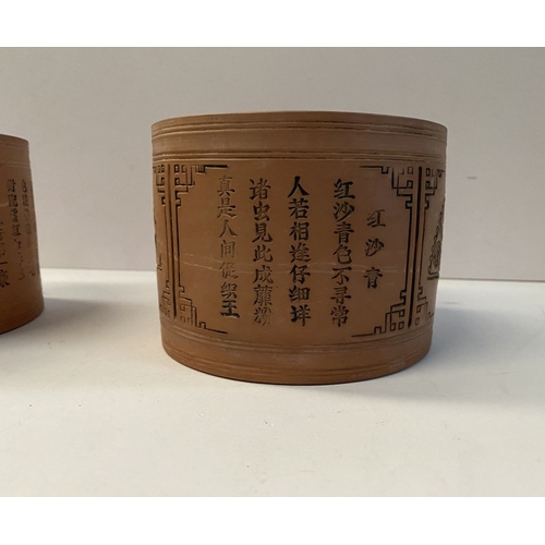 199 - A PAIR OF CHINESE RED CLAY CANNISTERS, cylindrical form, the sides decorated with panels depicting f... 