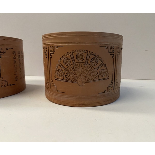 199 - A PAIR OF CHINESE RED CLAY CANNISTERS, cylindrical form, the sides decorated with panels depicting f... 