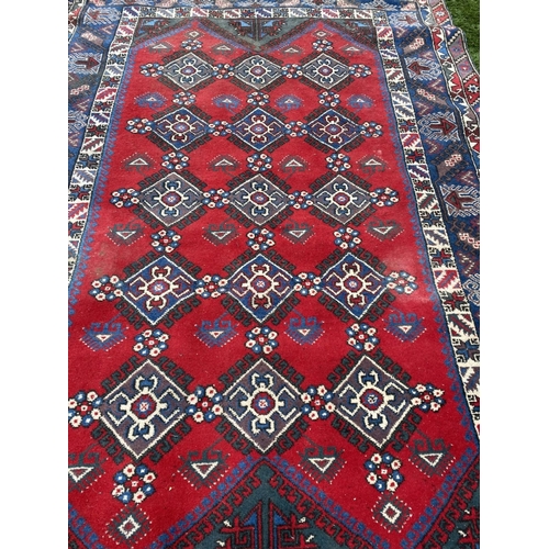 314 - A TURKISH KAZAK STYLE RUG, the centre with rows of geometric patterns on red ground, surrounded by m... 