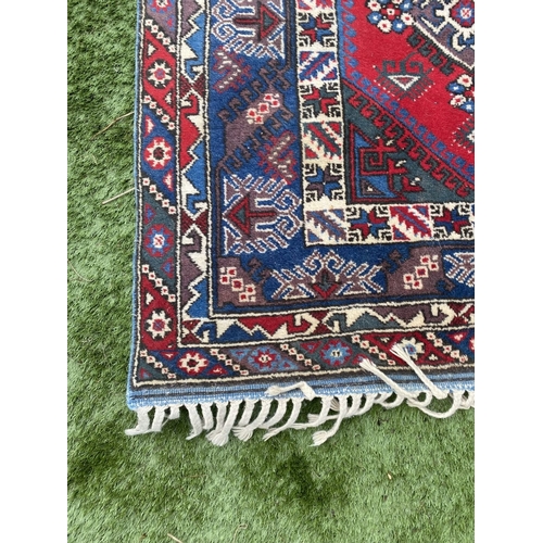 314 - A TURKISH KAZAK STYLE RUG, the centre with rows of geometric patterns on red ground, surrounded by m... 