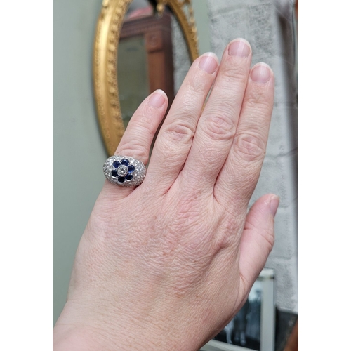 39 - A PRETTY 18CT WHITE GOLD SAPPHIRE & DIAMOND FLORAL CLUSTER / DRESS BOMBÉ SHAPED RING, the curved set... 