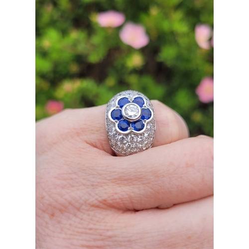 39 - A PRETTY 18CT WHITE GOLD SAPPHIRE & DIAMOND FLORAL CLUSTER / DRESS BOMBÉ SHAPED RING, the curved set... 