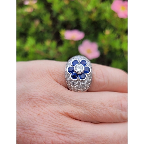 39 - A PRETTY 18CT WHITE GOLD SAPPHIRE & DIAMOND FLORAL CLUSTER / DRESS BOMBÉ SHAPED RING, the curved set... 