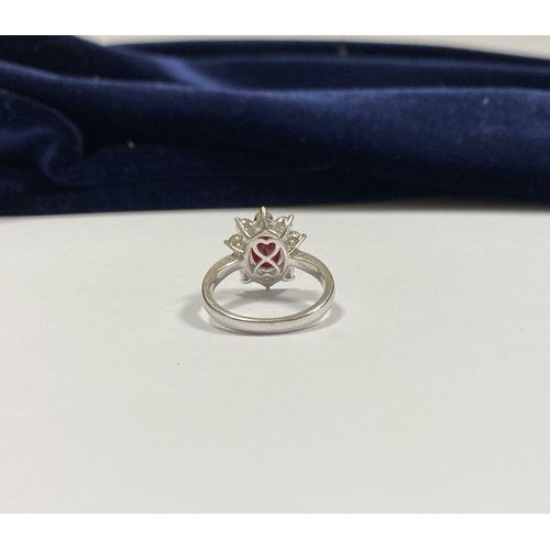 64 - AN 18CT WHITE GOLD BURMESE RUBY & DIAMOND CLUSTER RING, with central oval cut Burmese ruby in four c... 