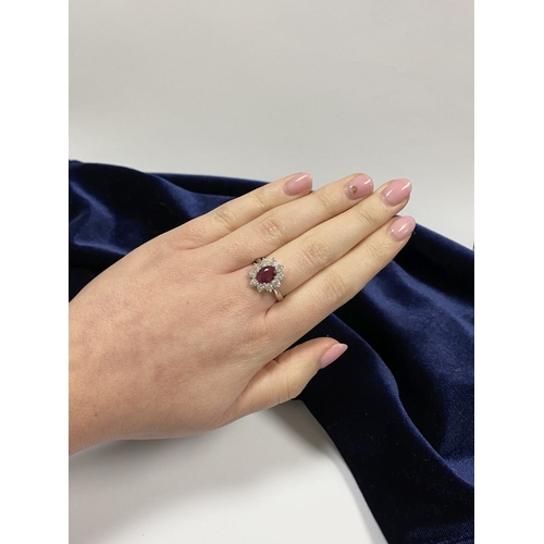 64 - AN 18CT WHITE GOLD BURMESE RUBY & DIAMOND CLUSTER RING, with central oval cut Burmese ruby in four c... 