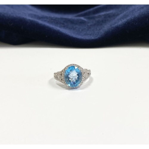 7 - AN 18CT WHITE GOLD BLUE TOPAZ & DIAMOND CLUSTER RING, complete with diamond encrusted shoulders, vib... 