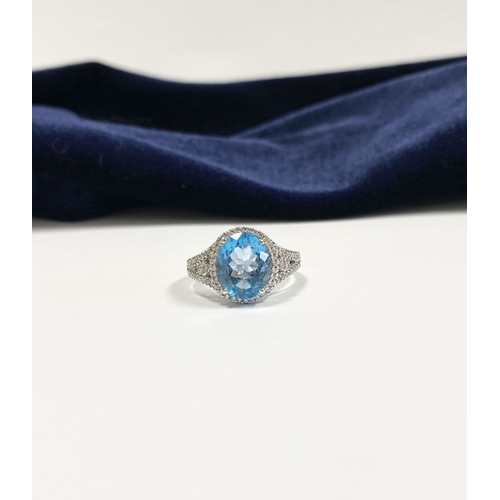 7 - AN 18CT WHITE GOLD BLUE TOPAZ & DIAMOND CLUSTER RING, complete with diamond encrusted shoulders, vib... 