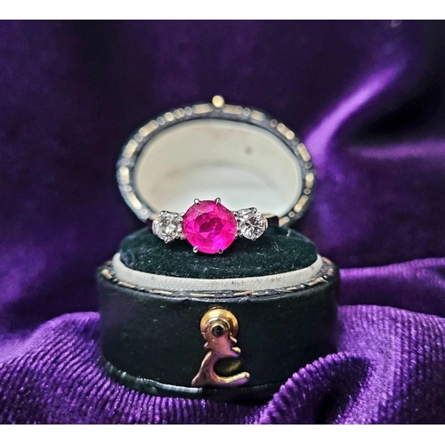 86 - A LOVELY THREE STONE DIAMOND & RUBY RING, with a central bright pink Burma ruby round cut stone, fla... 