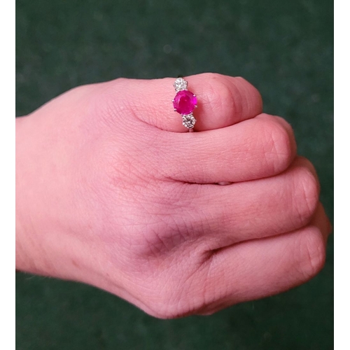 86 - A LOVELY THREE STONE DIAMOND & RUBY RING, with a central bright pink Burma ruby round cut stone, fla... 