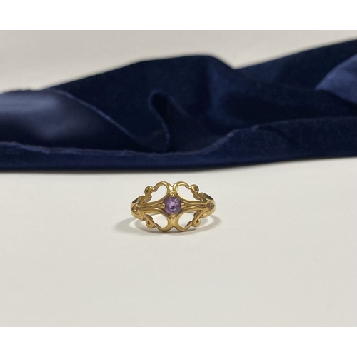 121 - A PRETTY 9CT YELLOW GOLD AMETHYST RING, with central round cut amethyst, in ornate scrolling openwor... 